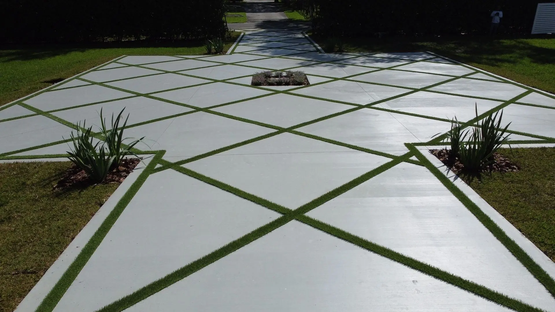 Diamond-pattern concrete driveway with artificial grass in Davie, Florida