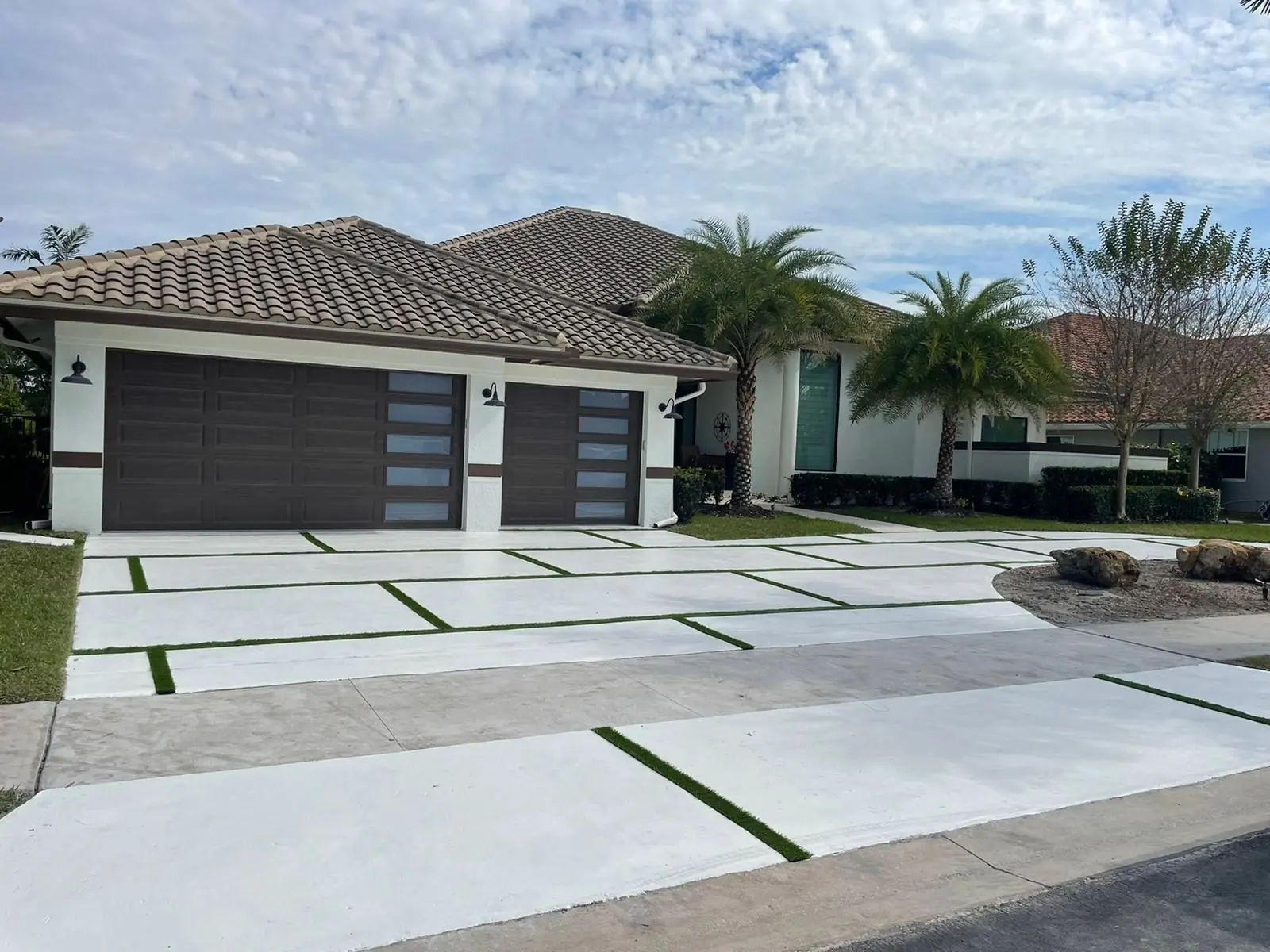 Modern white concrete driveway with artificial grass joints at a Weston, Florida home