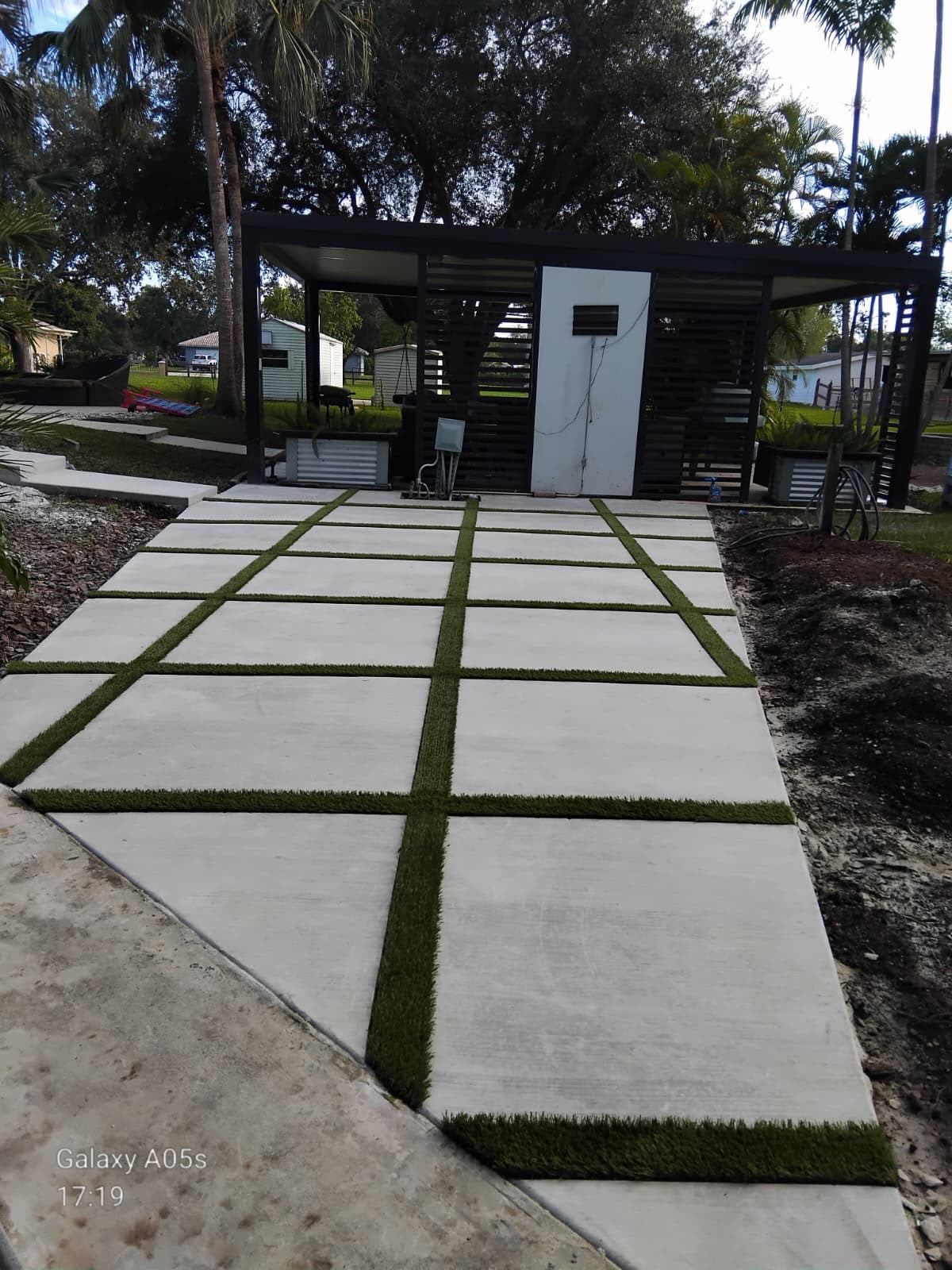 Concrete slab walkway with turf joints leading to a modern pergola, Broward County, Florida