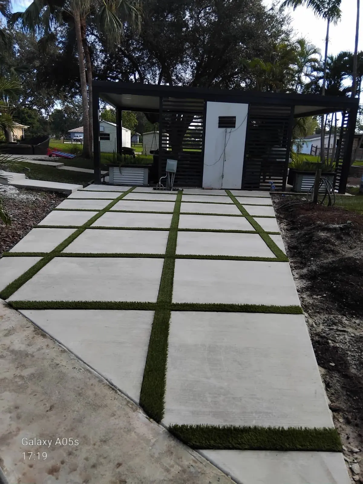 Concrete slab walkway with turf joints leading to a modern pergola, Broward County, Florida