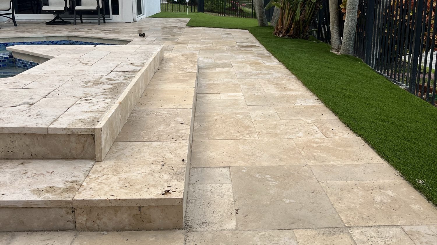 Travertine pool deck with raised spa wall and artificial turf by Concrete Solutions Today, Coral Springs, FL
