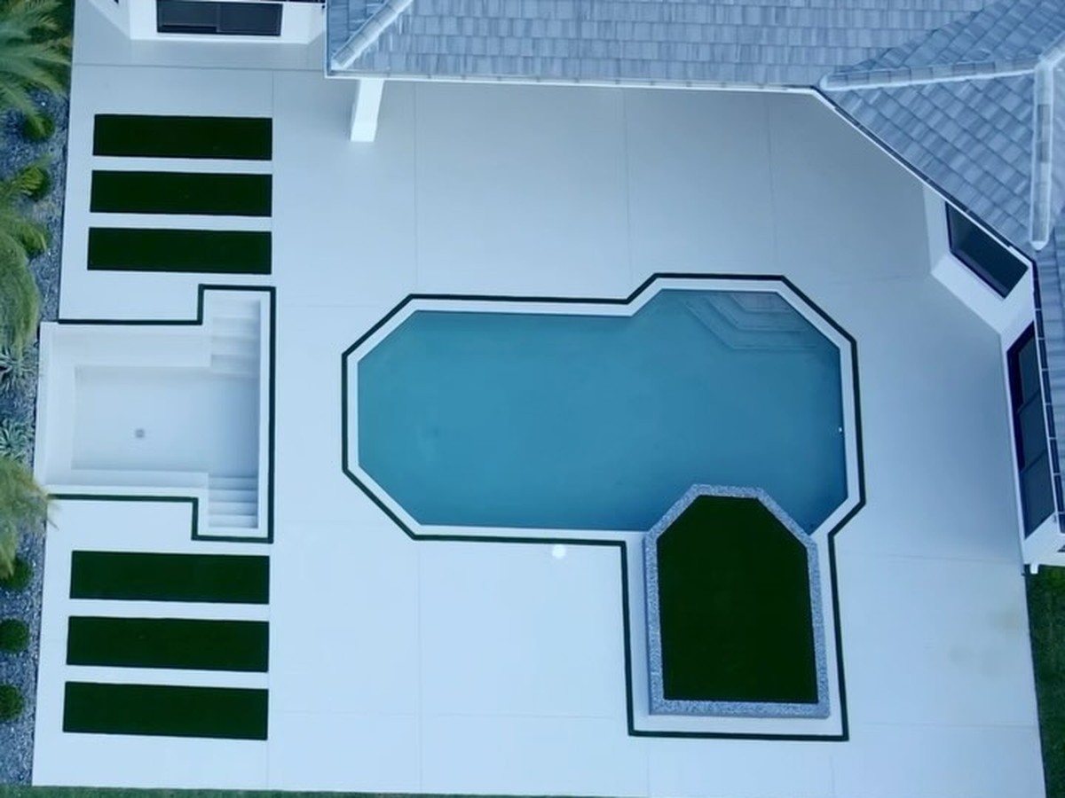 Aerial view of a California minimalist concrete pool deck with a sunken lounge and artificial grass accents at a Davie home