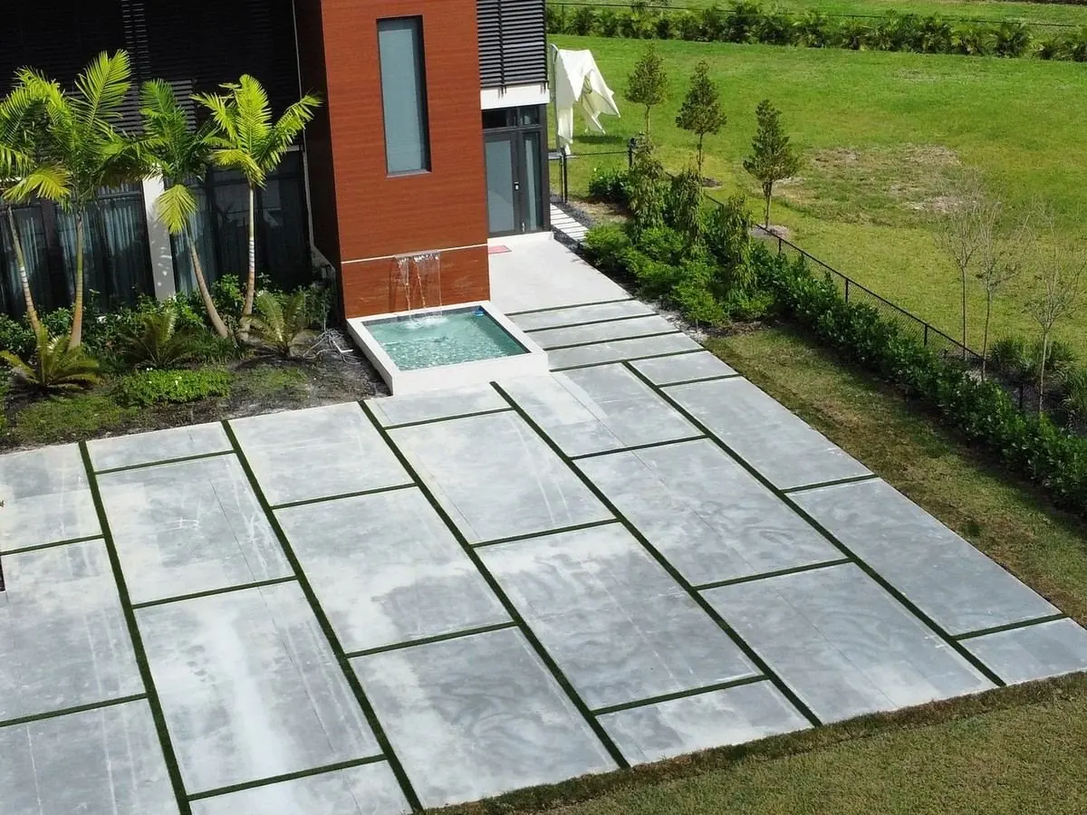 Modern concrete and artificial grass driveway with a water feature, aerial view by Concrete Solutions Today, Davie, FL