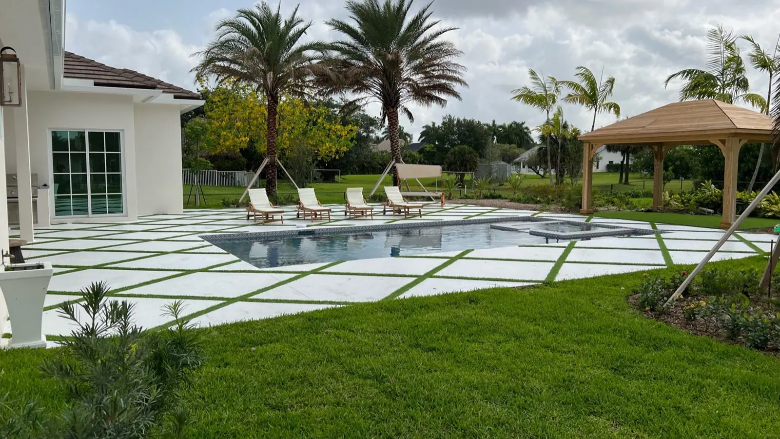 Concrete pool deck with turf joints and gazebo, wide view by Concrete Solutions Today, Fort Lauderdale, FL