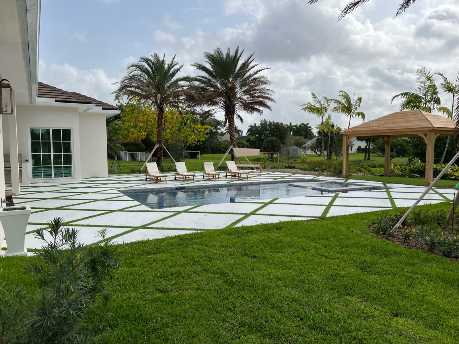Concrete pool deck with artificial turf joints and a wood gazebo built by Concrete Solutions Today in Fort Lauderdale, FL