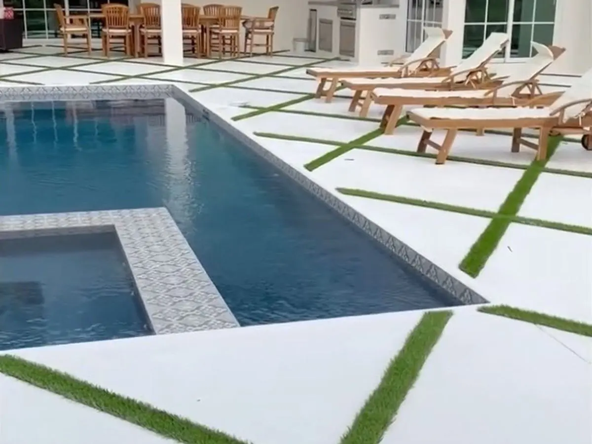 White concrete pool deck with diagonal artificial grass joints by Concrete Solutions Today, Parkland, FL