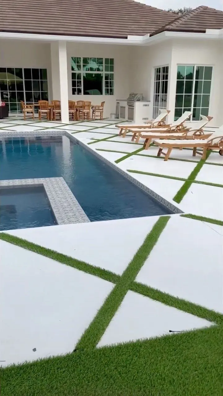 Pool deck with diagonal artificial grass lines, spa and outdoor kitchen by Concrete Solutions Today, Parkland, FL