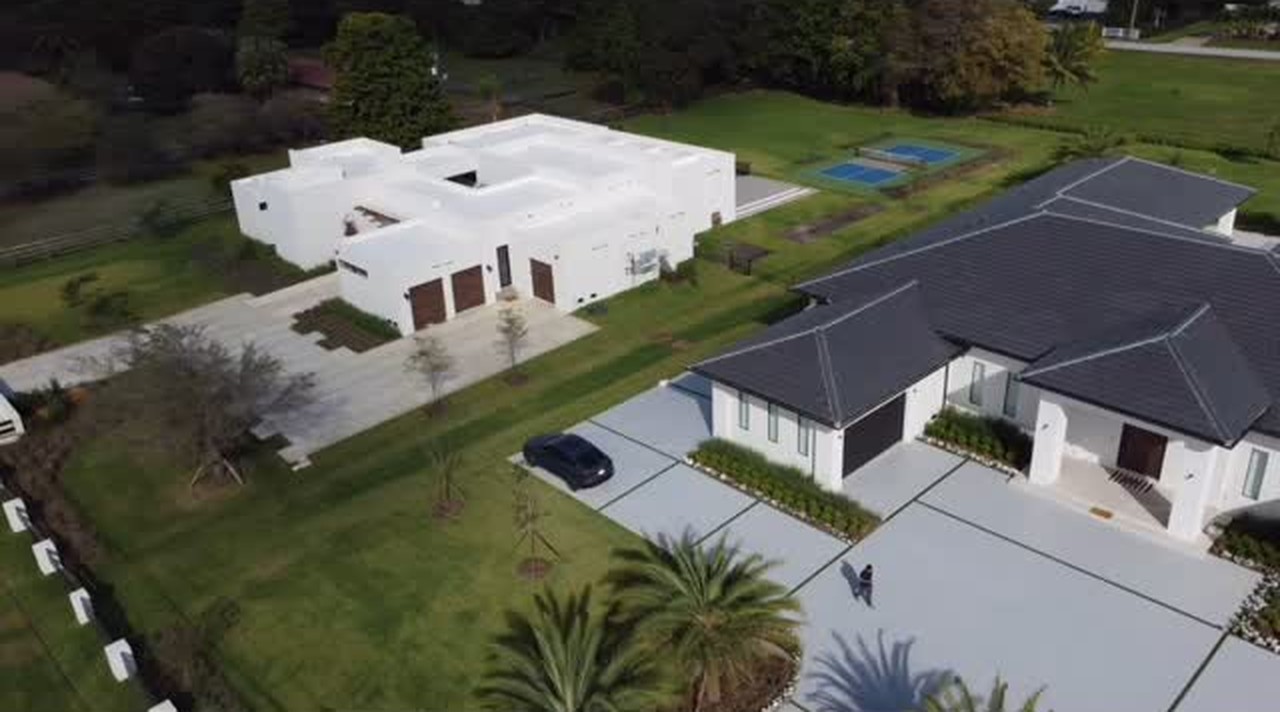 Aerial view of a new-construction home in Plantation with a concrete and artificial grass driveway and a backyard pickleball court by Concrete Solutions Today