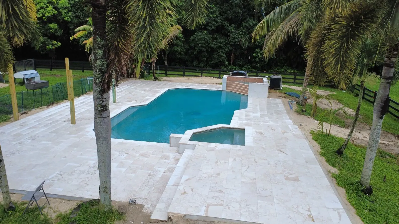 Pool and spa with a travertine-style paver deck by Concrete Solutions Today, Broward County, FL