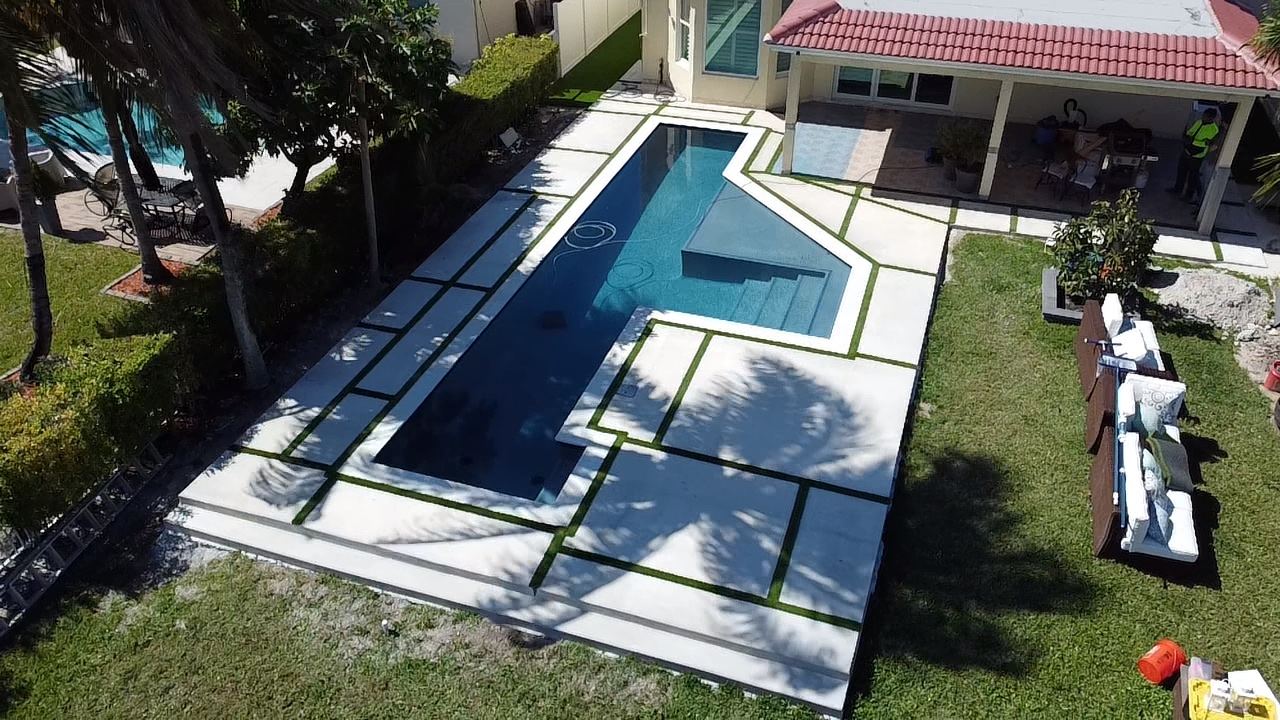 Deck de piscina con losas grandes de concreto y juntas de grama, condado de Broward, Florida