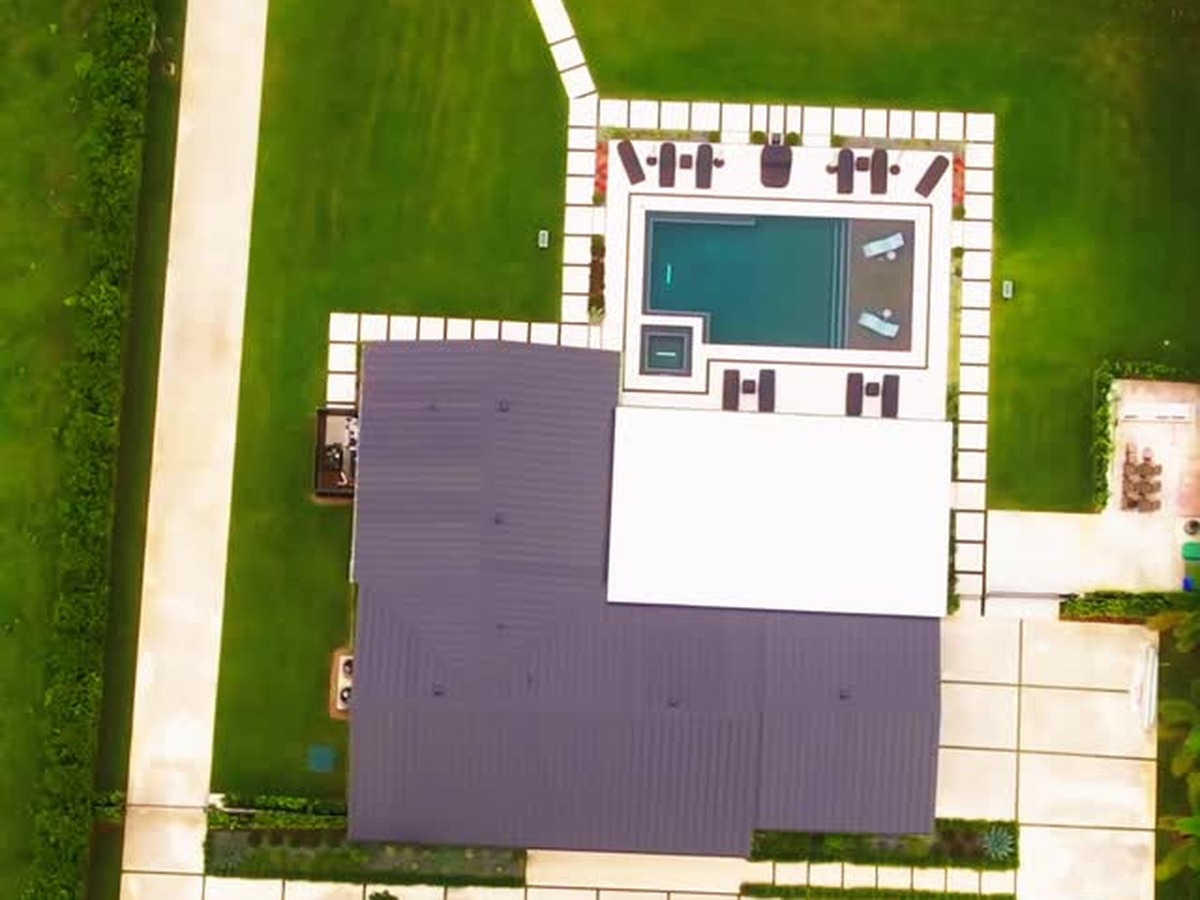 Aerial view of a saltwater pool, spa, natural stone deck, and aluminum pergola at a Southwest Ranches home built by Concrete Solutions Today